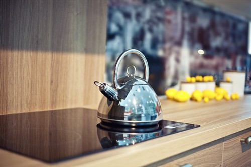 stainless steel kettle on glass stovetop in wood kitchen